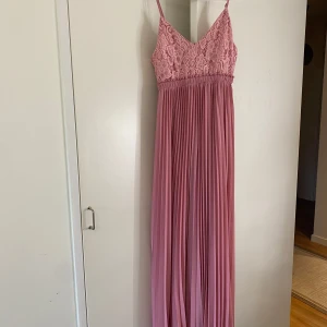 Rosa långklänning med spetsdetaljer - Elegant rosa långklänning med spetsdetaljer på överdelen och smala axelband. Kjolen är plisserad vilket ger en fin rörelse. Perfekt för speciella tillfällen. Super fin och skön till sommaren, fester och när som helst✨😁🥰💞priset går att diskutera!!