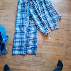 Rutig pyjamasbyxa med snörning - Mysiga pyjamasbyxor i blått och vitt rutmönster. Byxorna har en bekväm passform med snörning i midjan för justerbarhet. Perfekta för en avslappnad hemmakväll.