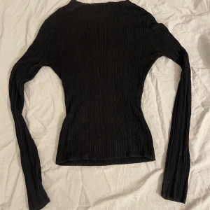 Svart ribbad tröja från BikBok - Säljer en svart ribbad tröja från BikBok. Tröjan har en tight passform och långa ärmar, perfekt för en stilren look. Materialet är lätt och stretchigt vilket gör den bekväm att bära. Passar bra till både jeans och kjol. Hör av dig vid intresse!