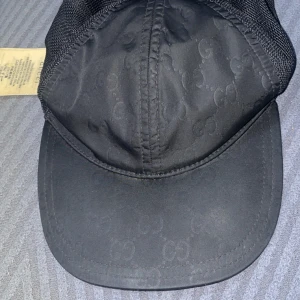 Svart keps med mönster - Snygg svart keps med diskret mönster och justerbart spänne bak. Perfekt för en stilren look.