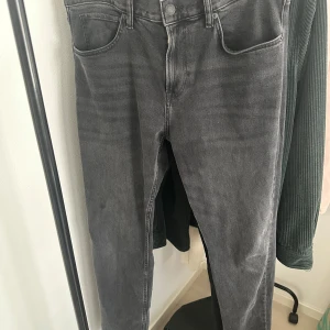 NY Grå slim/regular fit jeans från H&M  - Snygga grå slim fit jeans från H&M. De har en klassisk femficksdesign och är perfekta för en stilren look. Tillverkade i ett bekvämt material som ger en bra passform. Perfekta för både vardag och mer uppklädda tillfällen.