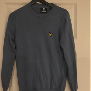 Blå tröja från Lyle & Scott - Säljer en stilren blå tröja från Lyle & Scott med deras ikoniska logga på bröstet. Tröjan har långa ärmar och en rund halsringning. Perfekt för en avslappnad och snygg look. Pris kan diskuteras via meddelanden!