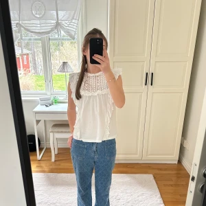 Vit blus med spetsdetaljer - Säljer nu min söta vita blus med spetsdetaljer och volanger. Sparsamt använt. Perfekt för vår och sommar💗💗