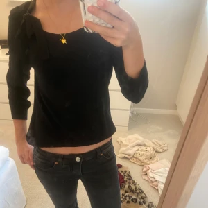 Svart topp med rosett - Snygg svart topp med trekvartsärm och en rosett på axeln. Storlek S!