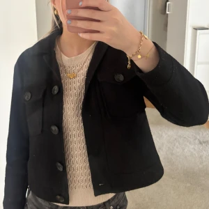 Svart kappa från Vero Moda - Snygg svart kappa från Vero Moda med knappar framtill. Lite nopprig