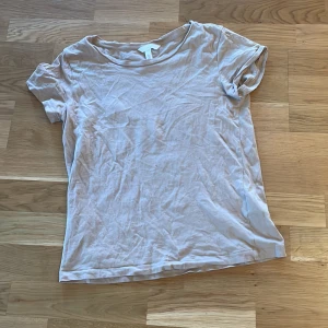Beige t-shirt från H&M - Säljer en enkel och stilren beige t-shirt från H&M. Den har en rund halsringning och korta ärmar, perfekt för en avslappnad look. Passar bra till både jeans och kjol.