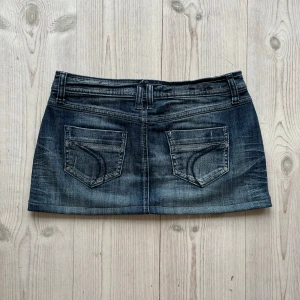 Blå lågmidjad jeanskjol  - Lågmidjad jeanskjol från Street One som jag har sytt upp från en längre kjol. Fint skick. Kan inte hitta storlek men skulle säga S/M. Tvärs över midjan är det 39 cm och den är 29 cm lång. Använd gärna köp nu!