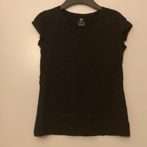 Svart t-shirt från H&M - Säljer en svart t-shirt från H&M i ekologisk bomull. T-shirten har en enkel design med korta ärmar och rund hals. Perfekt för en avslappnad stil. Nästan helt oanvänd, använd ett fåtal gånger. Lite knopprig i tyget annars helt orörd🤗 Förhandling vid priset kan diskuteras