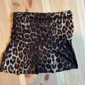 Leopardmönstrad kortkjol - Snygg leopardmönstrad kortkjol med en tight passform. Kjolen har en volangdetalj längst ner som ger en extra touch. Perfekt för att sticka ut med ett djärvt mönster.