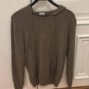 Brun cashmere hoodie från John Henric - Säljer en mjuk och stilren brun hoodie från John Henric i 100% cashmere. Den är i ett bra skick men har gått sönder lite där på toppen som jag visa. Men inget man tänker på. Annars är den jätte skön och snygg 