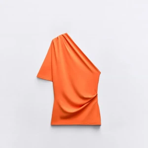 Orange one-shoulder topp - Snygg orange one-shoulder topp i ett mjukt och följsamt material. Perfekt för att sticka ut med sin unika design och livfulla färg. Skulle säga att färgen är lite mörkare än vad den är på bilden men inte stor skillnad! Från ZARA