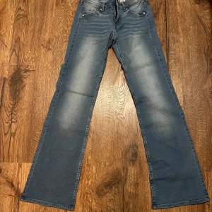 Blå bootcut jeans - Snygga blå bootcut jeans med låg midja. Perfekta för en avslappnad stil. Klassisk femficksdesign och tillverkade i denim.