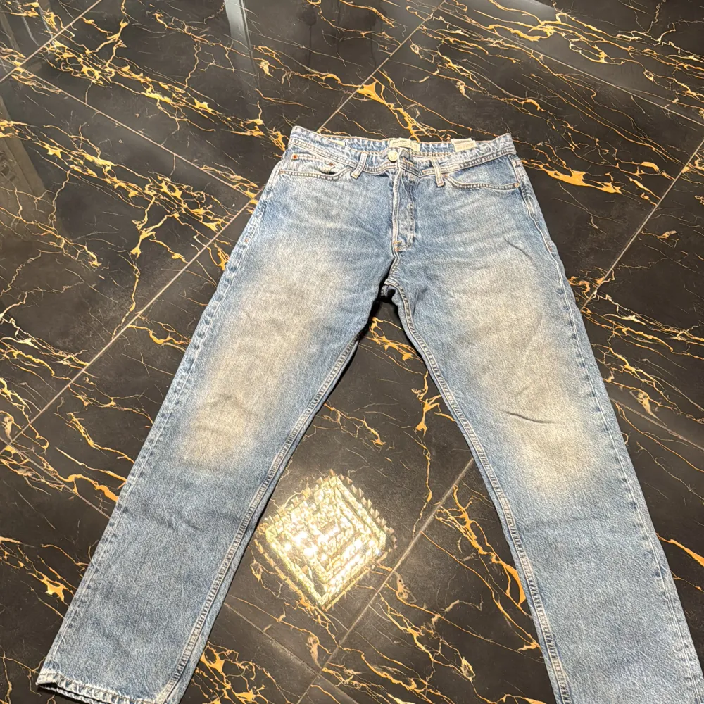 Två par klassiska jeansbyxor i blått och grått. De har en rak passform och är tillverkade i denim. Perfekta för en avslappnad stil. De två första bilderna är på ett par blå jeans från Jack and Jones (strl 33/34) och bild 3 och 4 är ett par grå jeans från lager 157 (strl 30/32) 100kr styck. Farkut & Housut.