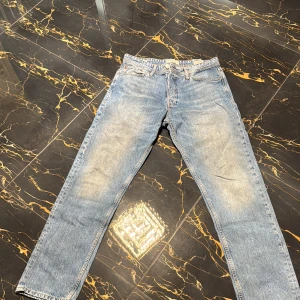Blå och grå jeans  - Två par klassiska jeansbyxor i blått och grått. De har en rak passform och är tillverkade i denim. Perfekta för en avslappnad stil. De två första bilderna är på ett par blå jeans från Jack and Jones (strl 33/34) och bild 3 och 4 är ett par grå jeans från lager 157 (strl 30/32) 100kr styck