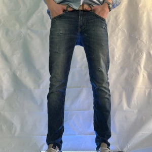 Mörkblå jeansbyxor från Lee - Snygga mörkblå jeans med en klassisk femficksdesign och lätt slitna detaljer. Byxorna har en slim passform och är perfekta för en stilren look. De är tillverkade i ett bekvämt denimtyg som ger en skön känsla hela dagen. 