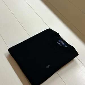 Svart tröja från Polo Ralph Lauren - Säljer en stilren svart tröja från Polo Ralph Lauren i merinoull. Tröjan har en slim fit passform och är långärmad med en diskret broderad logga på bröstet. Perfekt för våren och sommaren. Storlek L, sitter som M