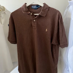 Ralph Lauren pikétröja - Polo Ralph Lauren pikétröja Storlek: M  (sitter perfekt M och L) | Färg: brun Klassisk modell, i fint skick – inga fläckar eller slitage. Kvalitativ och tidlös, passar både till vardags och finare tillfällen.✨👕  Snabb leverans 🚚 och extra bilder får du gärna fråga om!