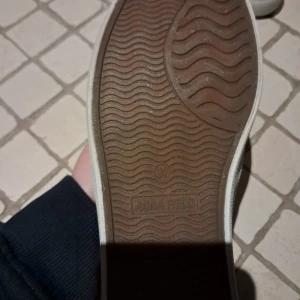 Gröna slip-on sneakers från Anna Field - Snygga gröna slip-on sneakers från Anna Field med en unik knytdetalj över ovandelen. Skorna har en vit sula och ett prickigt mönster på insidan. Perfekta för en avslappnad stil.