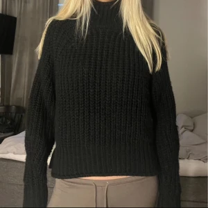 Svart stickad polotröja - Säljer en stilren svart stickad polotröja med hög krage. Tröjan har en croppad passform och långa ärmar, perfekt för kyligare dagar. En mångsidig och bekväm tröja som passar till det mesta. Hör av dig vid intresse!