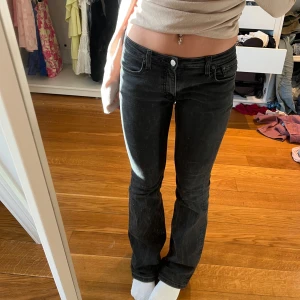 Svarta jeans - Snygga svarta jeans med låg midja och bootcut-stil. Byxorna har en klassisk femficksdesign och en knappgylf. Perfekta för en avslappnad look. 