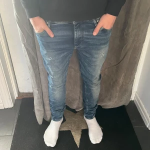 Jeans med slitningar - Snygga blå jeansbyxor med en slim passform. De har en klassisk femficksdesign och en dragkedja framtill. Perfekta för en avslappnad stil. W29 L30 men funkar som 30/30 