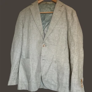 John Henric linnekavaj - Snygg ljusgrön kavaj med två knappar framtill. Perfekt för en stilren look. Kavajen har en klassisk passform och är tillverkad i ett lätt material som passar bra för varmare väder.