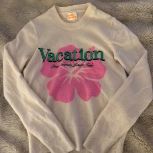 Vit tröja med rosa blomma från From Future - Supersöt vit tröja från From Future med stor rosa blomma och grön text 'Vacation' broderad på bröstet. Mjuk och skön, perfekt för dig som gillar statement-plagg. Rund hals och långa ärmar, tillverkad i kashmir för extra lyxig känsla. Pris kan diskuteras💕