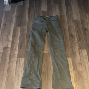 Khakigröna bootcut-byxor från Nelly - Snygga khakigröna bootcut-byxor från Nelly med klassisk femficksdesign och coola broderade detaljer på bakfickorna. Byxorna har låg midja och är gjorda i ett mjukt bomullsmaterial som sitter skönt hela dagen. Perfekt för dig som gillar en avslappnad men trendig look.