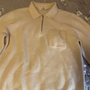 Beige ribbad half zip tröja H&M - Snygg beige ribbad tröja från H&M med krage och half zip framtill. Tröjan har en bröstficka och långa ärmar, perfekt för dig som gillar en chill och stilren look. Materialet är mjukt och känns skönt mot huden. Passar dig som vill ha en enkel men trendig tröja.