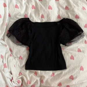 Svart topp med puffärmar - Svart topp från Dazy med bred, fyrkantig halsringning och stora puffärmar i spets och mesh. Markerad som strl L men skulle mer säga M till passformen!💞