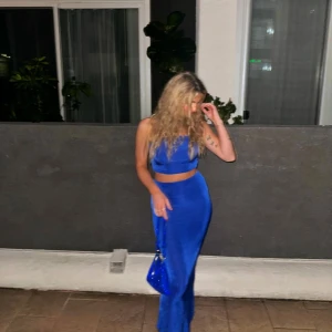 Blått set i ett glansigt och skönt material - Säljer ett snyggt blått bandeau topp set som är croppad och sitter tight men har även mycket stretch. Setet har en enkel, stilren design och är gjord i ett mjukt, stretchigt material som känns skönt mot huden. 