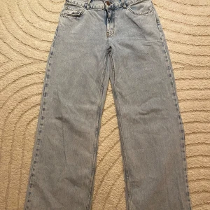 Ljusblå wide jeans med rå kant - Säljer ett par ljusblå jeans med breda ben och rå, fransig kant upptill. Klassisk femficksmodell med dragkedja och knapp. Jeansen har en chill, loose passform och är perfekta för dig som gillar en avslappnad stil.