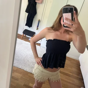 Mörkblå smockad linnetopp med knyt - Supersöt mörkblå linnetopp med smockad överdel och volang nertill. Axelbanden knyts på axlarna för en personlig touch. Går också att använda som kjol.