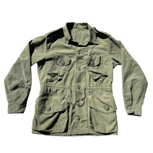 Kanadensisk fieldjacka 80-tal - Säljer denna fina jackan från 80-talets kanadeniska militär. Köpt på broadway & sons i stockholm men säljer då den tyvärr var för kort i ärmarna. Små tecken av användning här och där men det kan man förvänta sig då jackan är 40 år gammal. Plagglängd: 63cm Armlängd fr armhåla: 47cm Bröstvidd: 52cm. Om du har några funderingar så är det bara att du hör av dig!