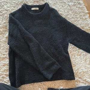 Svart stickad tröja från Gina Tricot - Mysig svart stickad tröja från Gina Tricot i storlek XS. Tröjan har en klassisk rund halsringning och ribbade muddar vid ärmslut och nederkant. Perfekt för kyliga dagar och enkel att matcha med jeans eller kjol. Tröjan ingår i ginatricots premium version och är därför köpt för ca 400-500kr. Helt oanvänd. Så sjukt bra kvalité.