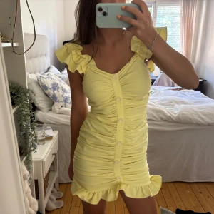Gul kort klänning med volanger - Supersöt ljusgul klänning med volangdetaljer på axlar och längst ner!
