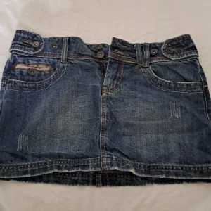 Mörkblå jeans tjol medel lång yk2 style - Jättefina jeans kjol som är medel lång. Den har många fina detaljer. Köpt från en marknad i Thailand. Står inte storleken men ungefär 38