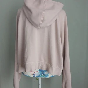 Kort Ljusrosa hoodie från H&M Divided - Superskön och trendig cropped hoodie i mjuk ljusrosa färg. Perfekt för en avslappnad men stylish look – funkar året runt!  stl XL, sitter snyggt och visar lite midja. Mjuk fleece på insidan gör den extra mysig. Lite blekare i färgen är nyskick.