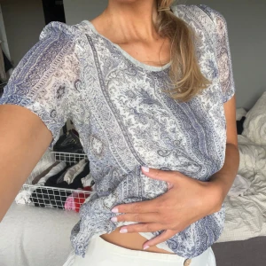 Blåvit mönstrad blus med kort ärm - Säljer en tunn och luftig blus med korta ärmar i blått och vitt paisley-mönster. Från massimo dutti 