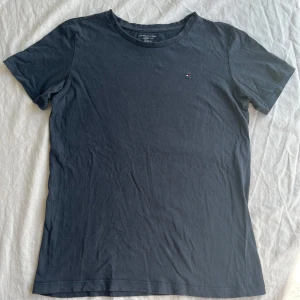 Mörkblå t-shirt Tommy Hilfiger - Snygg mörkblå t-shirt från Tommy Hilfiger med klassisk rund hals och liten broderad logga på bröstet. Modellen är enkel och stilren. Är i bra skick, hel o ren. Storlek 152/164. (nypris 200kr)