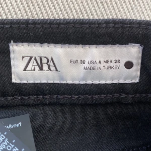 Svarta bootcut jeans från Zara stl 36, knappt använda, köpta för 559 - Snygga svarta jeans från Zara i bootcut-modell, storlek 36. Klassisk femficksdesign med bälteshällor och knappstängning. Jeansen har en mörk ton och är tillverkade i ett stretchigt bomullsmaterial som sitter skönt hela dagen.