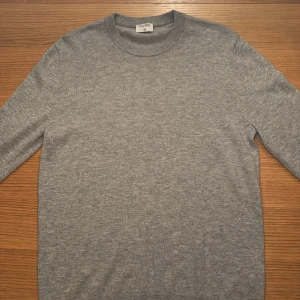 Grå stickad tröja från Filippa K - Säljer en riktigt fet merino ulls tröja från Filippa K. Tröjan är helt ny och nästan aldrig använd. Storlek M. Mjuk och skön kvalitet, perfekt för dig som gillar minimalistisk stil.
