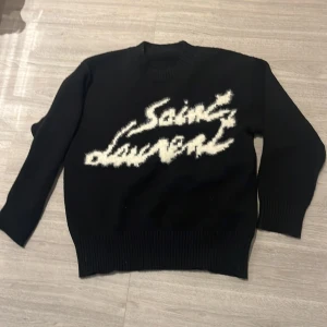 Svart stickad Saint Laurent tröja - ⚜️Säljer min Saint Lauren tröja !!. Då jag har tyvärr växt ur den och blev ett litet väl dyrt spontanköp. Tröjan är S men passar medium då den är lite baggy i modellen. Tröjan är 100% genuin och använd 5 gånger så den är så gott som ny. ⚜️