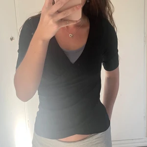 Svart omlottopp från Bondelid - Svart omlottopp från Bondelid i storlek XS. Topp med kort ärm, v-ringning och snygg omlottdesign som ger en stilren och modern look. Inte kommit till användning utan bara testad.