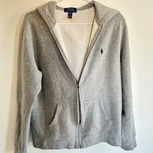 Grå hoodie från Polo Ralph Lauren - Snygg grå hoodie från Polo Ralph Lauren med dragkedja. Perfekt inför hösten. Först till kvarn😁