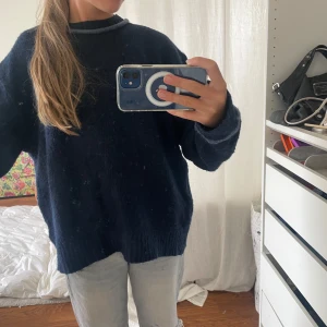 Mörkblå stickad tröja från Zara - Mysig mörkblå stickad tröja från Zara med ljusblå detaljer vid halsringning och ärmslut. Tröjan har en loose passform, rund hals och långa ärmar. Perfekt för dig som gillar chill och enkel stil med en touch av färg. Och en öppen rygg.