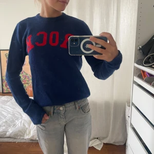 Blå stickad tröja Zadig & Voltaire - Snygg mörkblå stickad tröja från Zadig & Voltaire med röd text 'ROCK' framtill. Rund halsringning och långa ärmar. Perfekt för dig som gillar coola statement-plagg och vill ha något som sticker ut i garderoben.