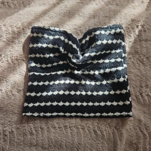 Randig svartvit stickad tubtopp - Säljer en tubtopp med svart och vit randigt mönster. Toppen är stickad och har en bandeauform med en liten twist framtill.