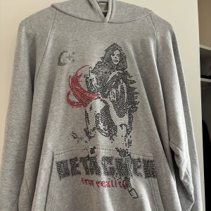 Grå hoodie med tryck - Säljer en grå hoodie från detached. Köptes några år sen för 1000 kr. Några få av stenarna har ramlat av, men det märks inte av! Den har luva och ficka på framsidan. Väldigt varm ock skön på hösten / vintern. Säljs på grund av att den inte används längre. Skriv om du har frågor!💗