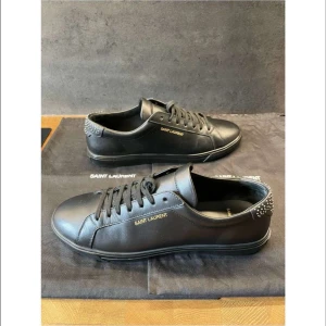 Svarta sneakers från Saint Laurent - Snygga svarta sneakers från Saint Laurent med. Skorna är i skinn med snörning och har silverfärgade nitar på hälen. Fint skick 